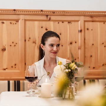 Gudruns Blog: alles über Sterzing, übers Wandern, über Tirol Frau sitzt am gedeckten Tisch mit Weinglas, Kerze und Blumen im Restaurant