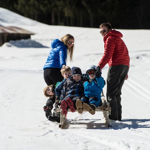 Das Skigebiet Ladurns und andere Winter-Highlights Familie beim Rodeln auf verschneitem Weg im Winter