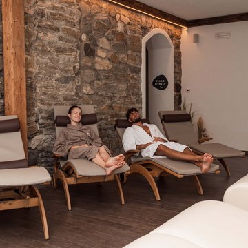 Gudruns Blog: alles über Sterzing, übers Wandern, über Tirol Zwei Personen entspannen auf Liegestühlen in einem Spa-Ruheraum vor Steinmauer