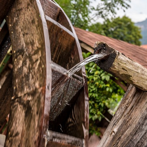 Hotel in Gossensass: welcome to Gudrun! Wasser fließt aus einem Holzausguss auf ein sich drehendes Wasserrad