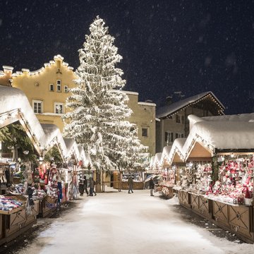 Gudruns Blog: alles über Sterzing, übers Wandern, über Tirol Verschneiter Weihnachtsmarkt mit beleuchtetem Tannenbaum und Hütten bei Nacht