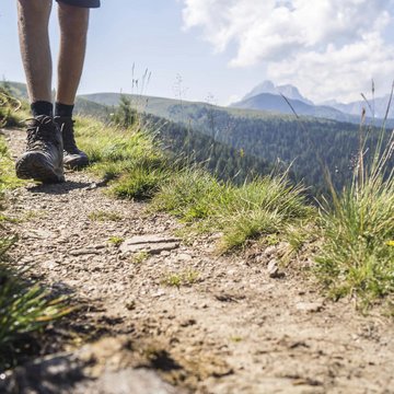 Gudruns Blog: alles über Sterzing, übers Wandern, über Tirol Wanderer mit Bergschuhen auf einem Bergweg mit Gras und Bergen im Hintergrund