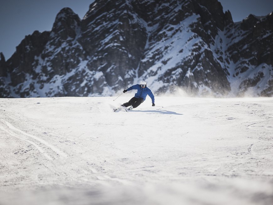 Das Skigebiet Ladurns und andere Winter-Highlights Skifahrer in blauer Jacke fährt in zerklüftigen Bergen auf Schnee