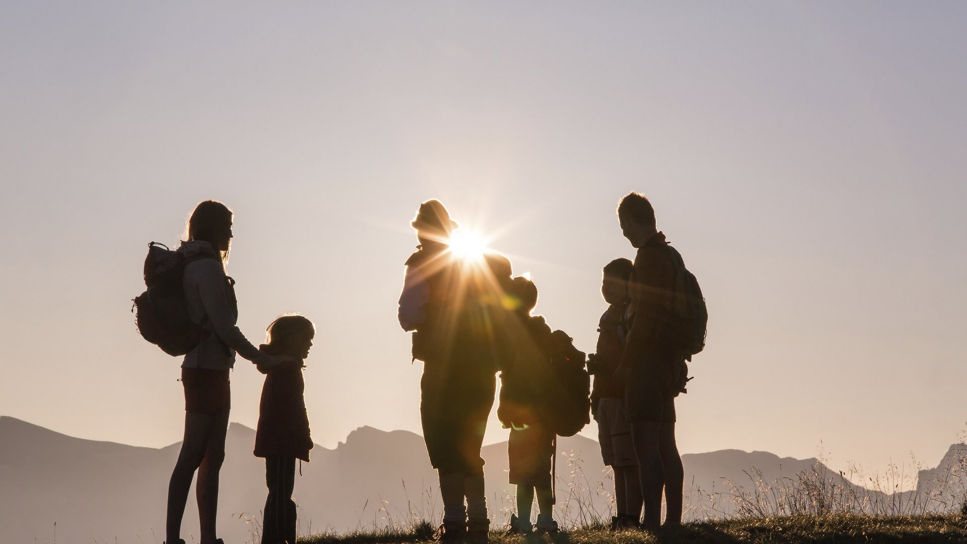Hotel am Brenner in Sterzing: Veranstaltungen Silhouetten einer Familie mit Rucksäcken bei Sonnenuntergang in den Bergen