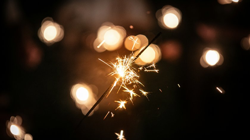 Gudrun in Feierlaune Funkelnde Wunderkerze vor verschwommenen Lichtern in dunkler Umgebung
