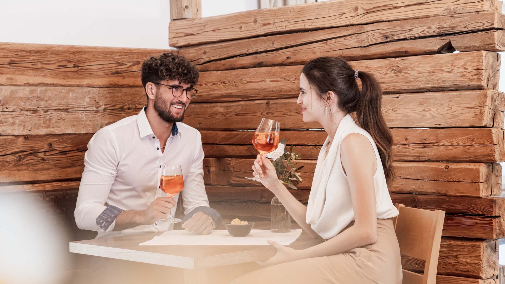 Eines der coolsten Hotels in Gossensass (Südtirol) Junges Paar trinkt Wein und unterhält sich in einem gemütlichen Holzrestaurant