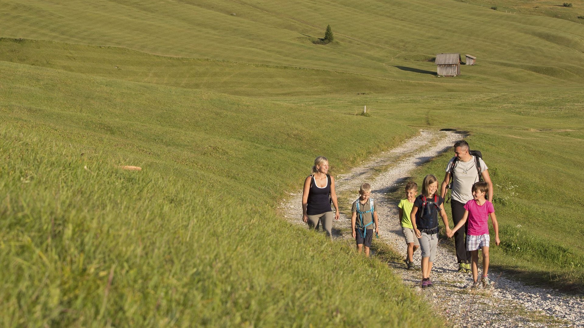 Unterkunft bei Ladurns für Familien Familie wandert auf einem Pfad in den grünen Alpen mit Bergen im Hintergrund