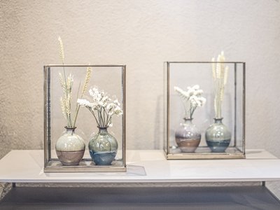 Hotel in Gossensass: welcome to Gudrun! Zwei Vasen mit Trockenblumen in Glasboxen auf einem weißen Regal