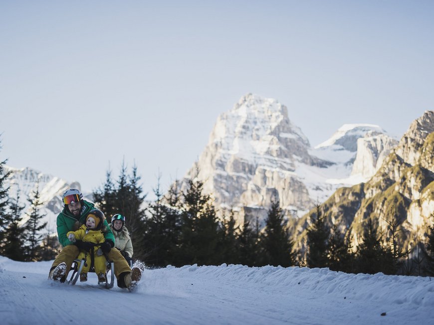 Das Skigebiet Ladurns und andere Winter-Highlights Familie genießt Schlittenfahrt im Schnee vor Bergkulisse