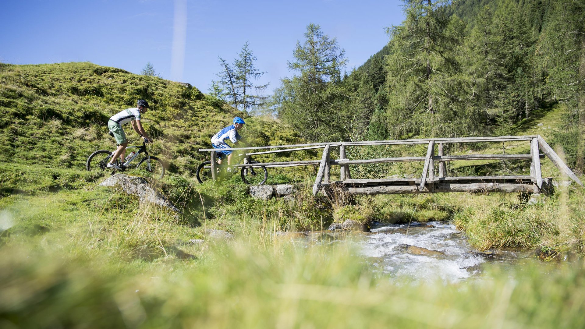 Hiking in Sterzing and the surrounding area Two cyclists crossing a wooden bridge over a mountain stream