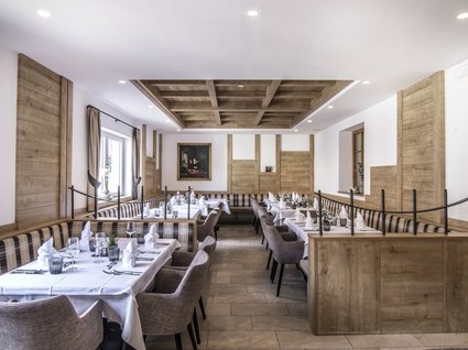 Gudrun in Gossensass: Hotel mit Herz Elegantes Restaurant mit Holzwänden und gedeckten Tischen mit weißen Tischdecken