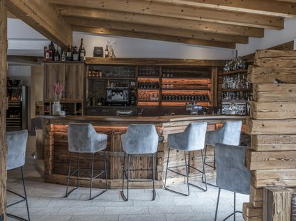 Gudrun in Gossensass: Hotel mit Herz Gemütliche Bar mit Holztheke und grauen Barhockern in rustikalem Stil