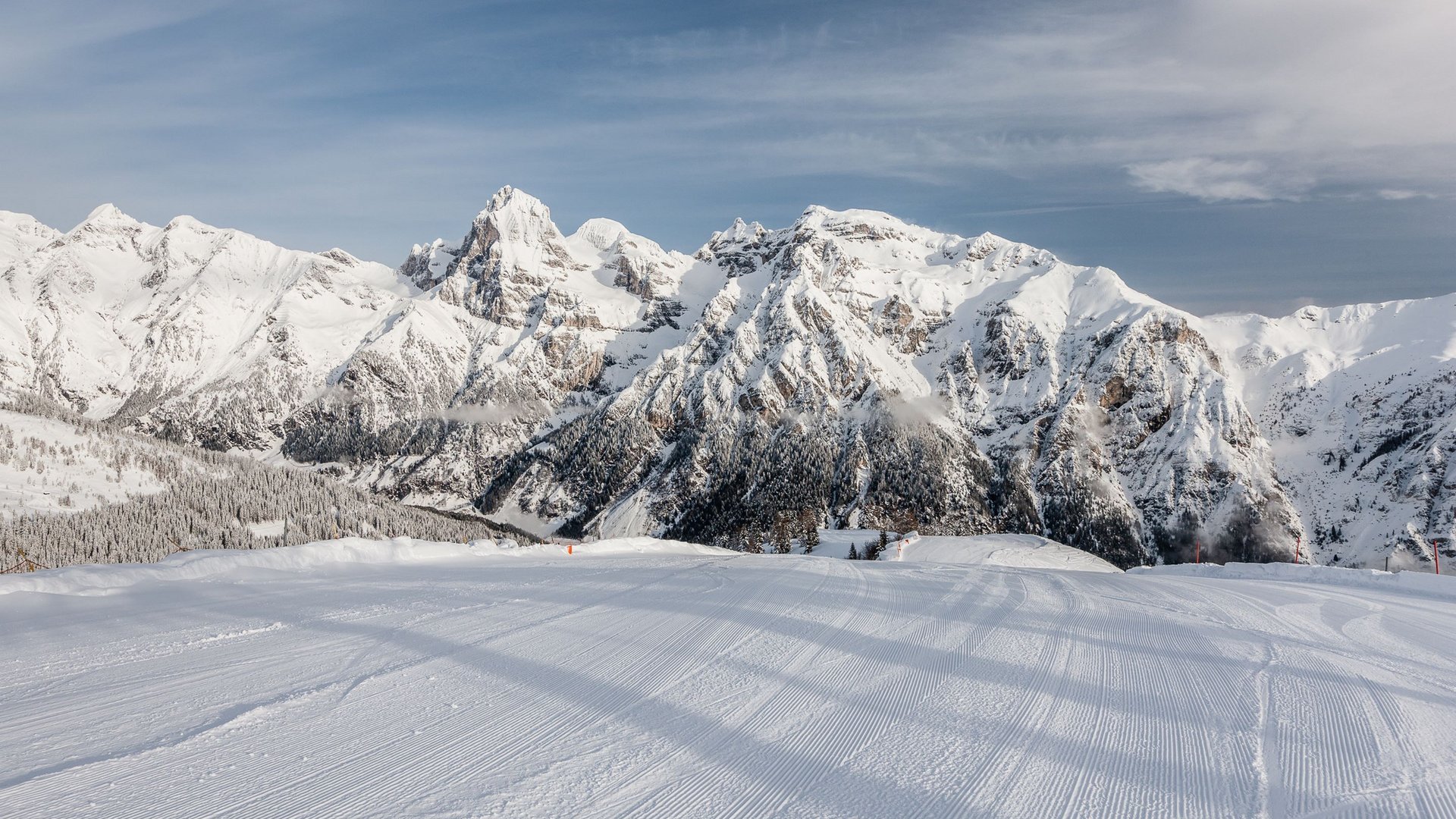 Gudrun in Gossensass: Hotel mit Herz Frisch präparierte Skipiste vor schneebedeckten Bergen unter blauem Himmel