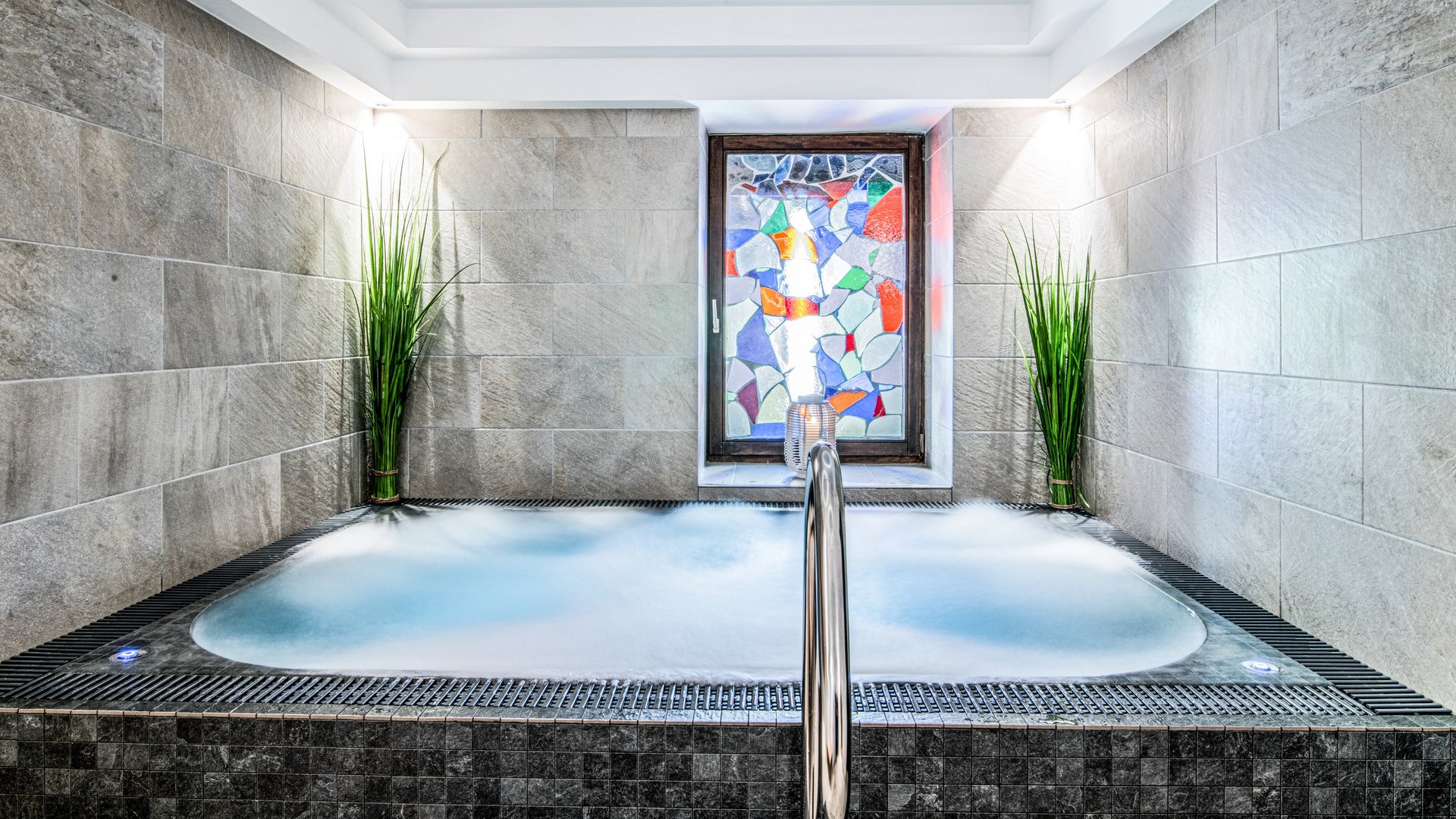 Gudrun in Gossensass: Hotel mit Herz Moderner Whirlpool mit buntem Glasfenster und Pflanzen in einem Wellnessraum