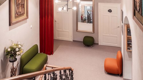 Hiking in Sterzing and the surrounding area Hallway with green and orange chairs, large mirror, and red curtain