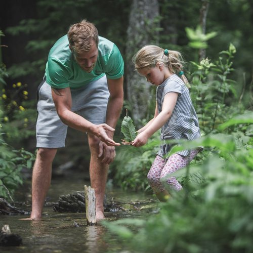 Hiking in Sterzing and the surrounding area Man and girl exploring a stream in the forest together